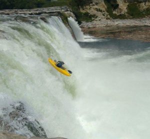 A kayaker dropping down a river waterfall while on class 5 whitewater rafting Colorado adventure