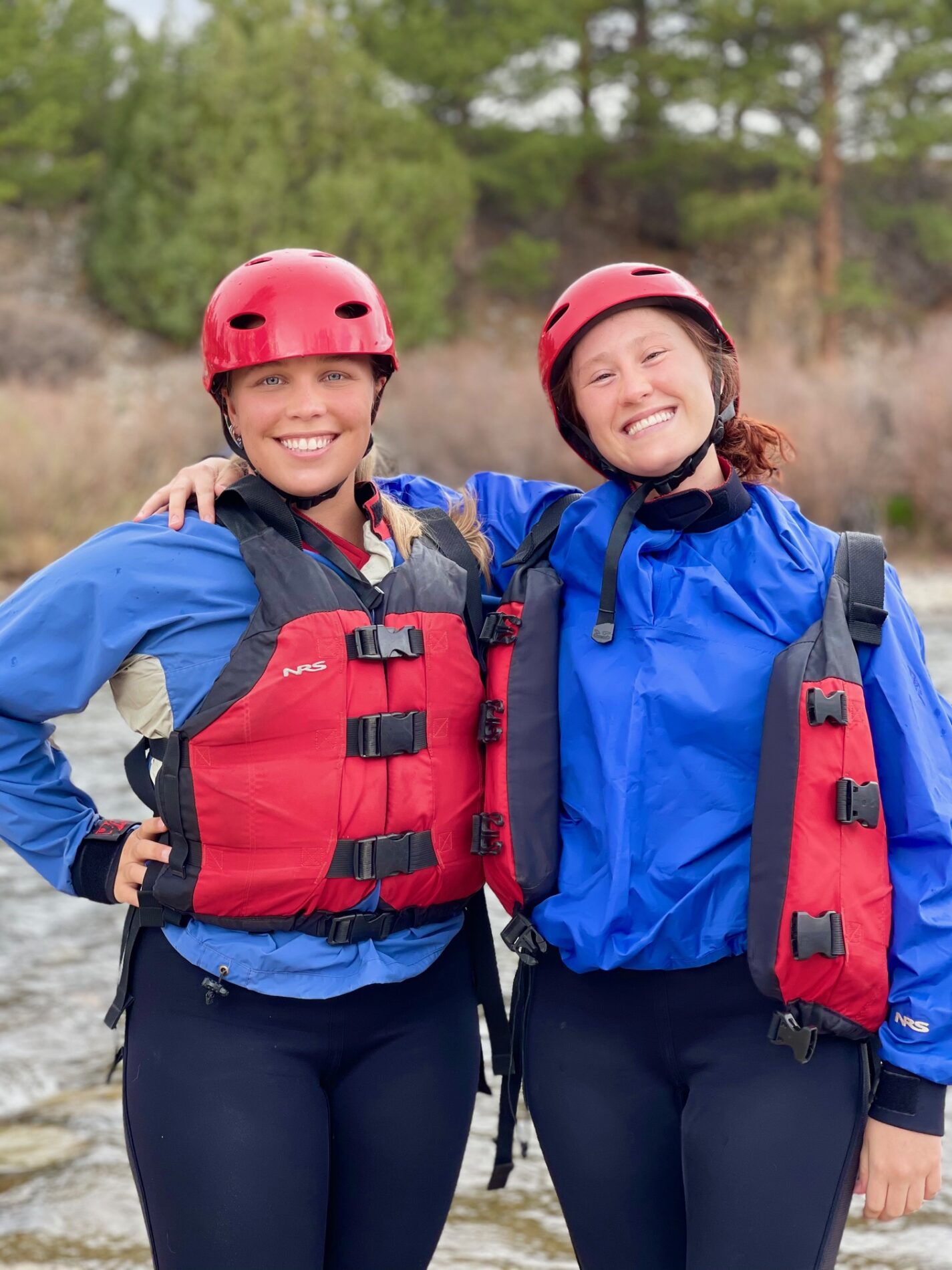 Two ladies posing while wearing personal floating devices before going on a whitewater rafting 