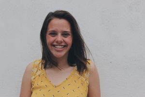 A class 3 whitewater rafting adventurer smiling while rocking her yellow-spotted sleeveless blouse