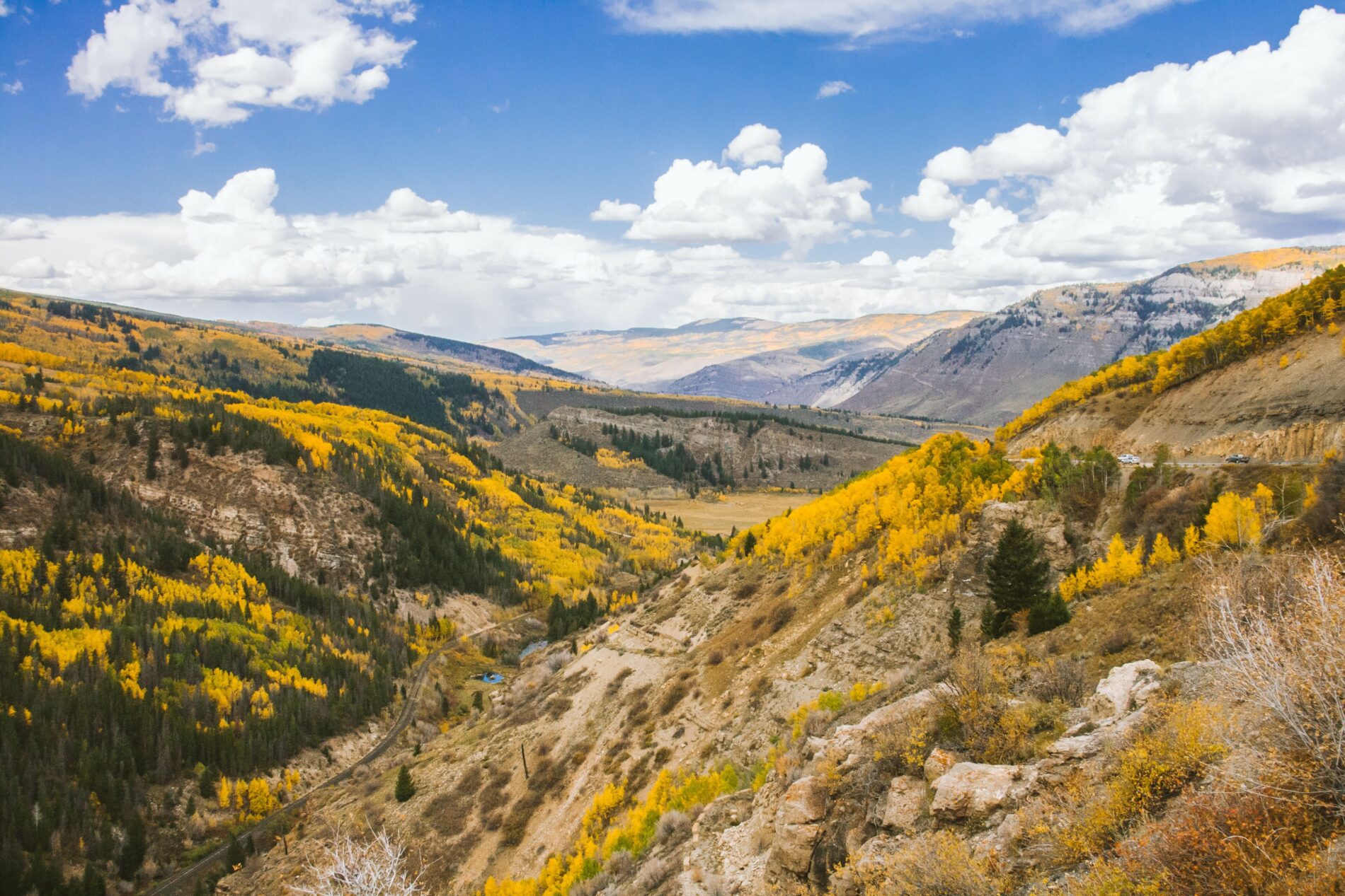Mountain landscape of a KODI Rafting destination with autumn trees, rocky terrain, and cloudy sky.