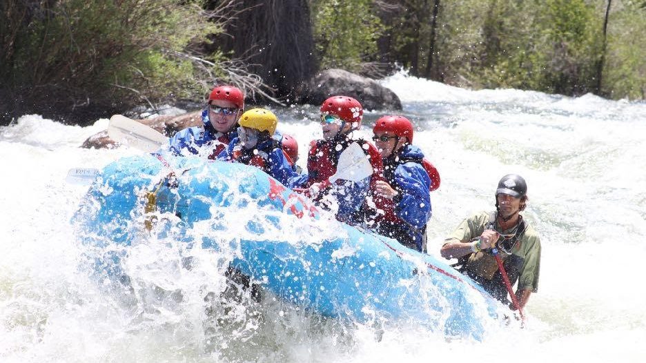 Rafting group and raft guide maneuvering turbulent rapids on a class 4 whitewater rafting adventure
